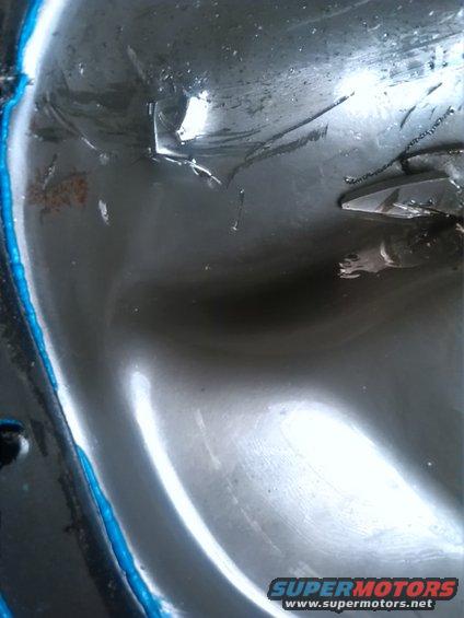 Black engine oil pan with blue gasket material and metal debris