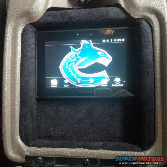 Interior view of a BlackBerry tablet in a vehicle's center console showing a Canucks logo
