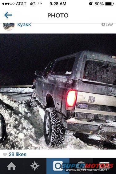 Rear view of a 1995 Ford Bronco stuck in snow, with 'JUCK FEEP' sticker on tailgate
