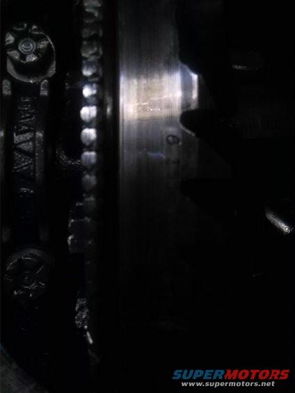 Close-up of a metal gear and bolt heads, with a partial serial number visible