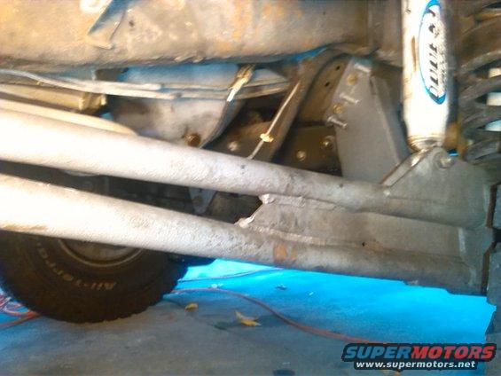 Vehicle underbody showing suspension components and a tire. Text 'SUPERMOTORS' visible