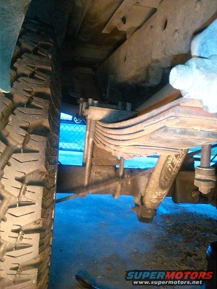 Underside view of a vehicle's rear leaf spring suspension and tire