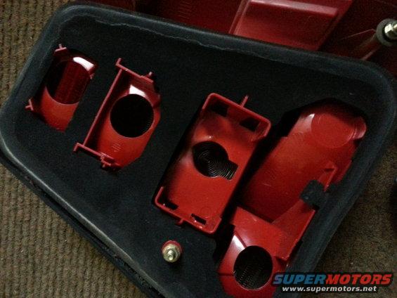 Red plastic housing for a car taillight assembly, with cutouts for bulbs