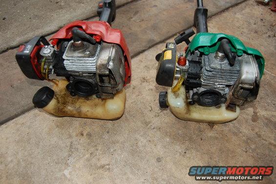 Two string trimmers, one with a red cover and one with a green cover, sit side-by-side on a concrete surface