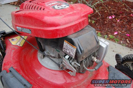 Red Toro lawnmower engine with visible spark plug and warning labels