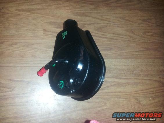 Black power steering pump with green and red hose fittings, text visible