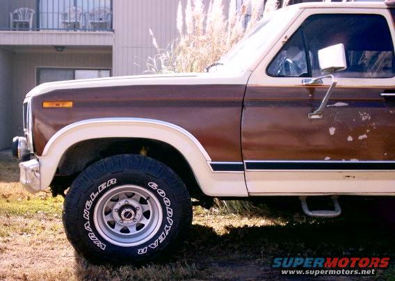 1980 Ford Bronco side view showing brown and cream paint, fender flare, and Goodyear Wrangler tire