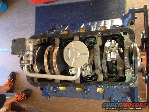 Engine block with crankshaft and oil pump visible. Someone's feet are in the lower left