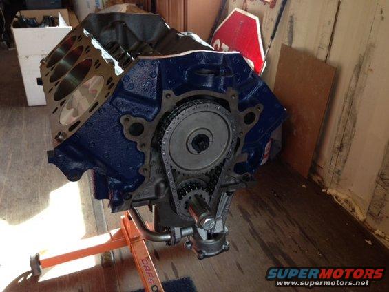 Blue engine block on an orange stand, showing timing chain and gears