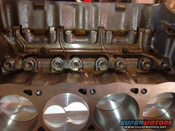 Engine block with pistons and valve train components. Supermotors.net logo visible