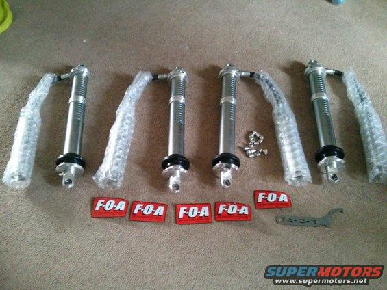 Four F-O-A shock absorbers and a wrench on a carpeted surface