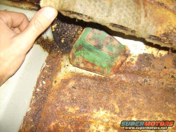 Rusted car floor with a green object partially visible