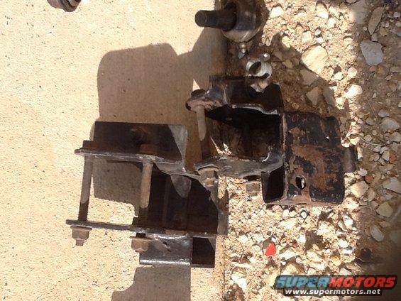 Engine mount bracket with bolts and rust, lying on the ground
