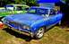 1964 Mercury Monterey - A blue pickup truck is parked next to a green car under a tent with a banner.