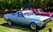 1964 Mercury Monterey - Two classic vehicles, a light blue pickup and a red sedan, are parked on grass with trees in the background.