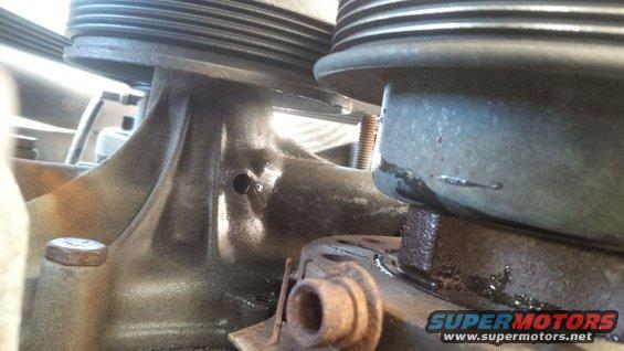 Close-up of a metal engine component with a ribbed pulley above it