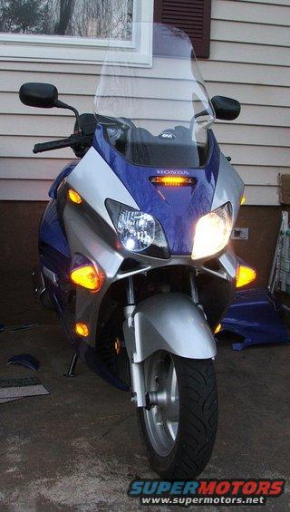 Blue and silver Honda scooter front view, with a clear windshield and orange turn signals