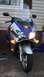 2006 Honda Reflex - A blue and silver Honda scooter is parked in front of a house, with its headlights and turn signals illuminated.