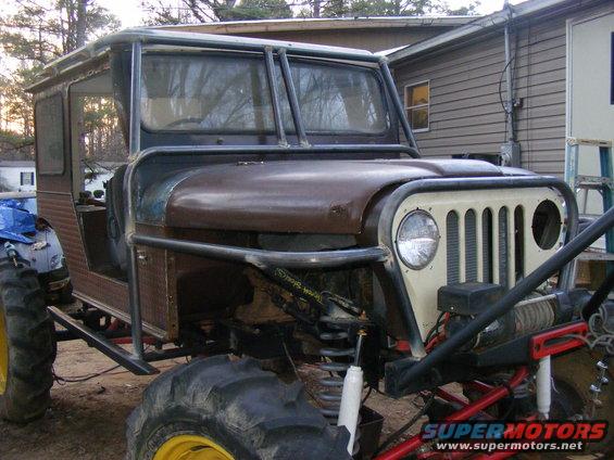 Custom off-road vehicle with large tires, roll cage, and winch. Front grille is cream-colored