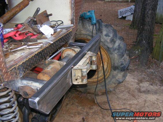 Close-up of a large tire and suspension components with tools and a drill nearby