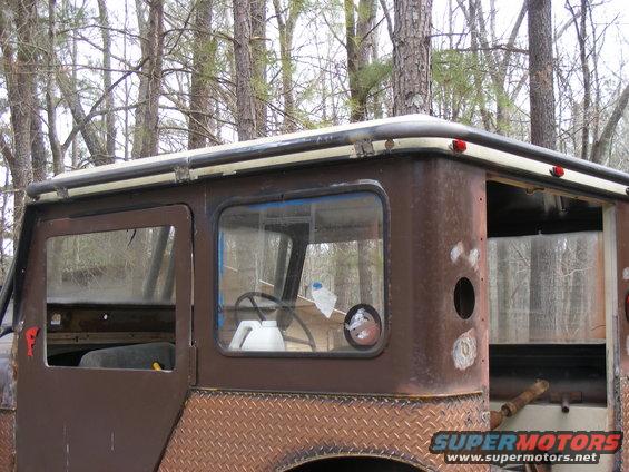 Side view of a rusty brown SUV with diamond plate trim and roll cage