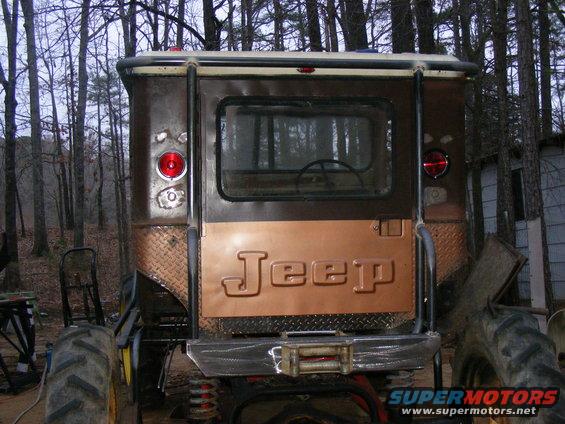 Rear view of a brown Jeep CJ-5 with a copper tailgate and large tractor tires