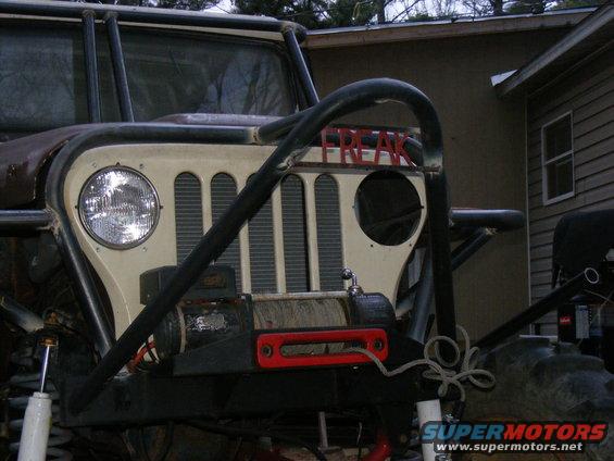 Modified off-road vehicle front end with a winch and a roll cage, painted "FREAK" on the grille