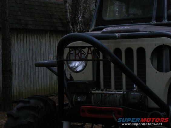 Front of a heavily modified Jeep CJ with a winch and roll cage. The word 'FREAK' is visible on the headlight