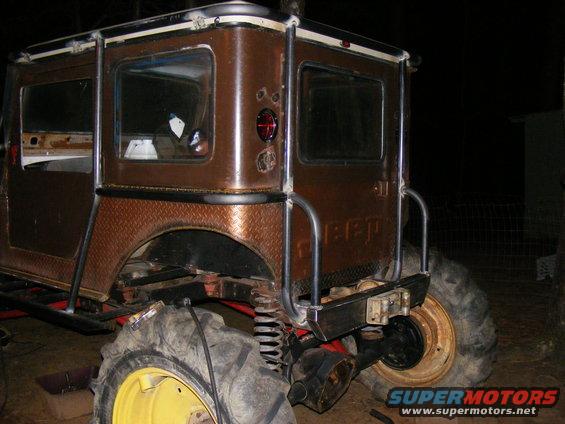 Custom brown off-road vehicle with large tires and roll cage. Looks like a modified Jeep