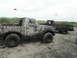 1980 Ford Bronco - Two off-road vehicles are heavily covered in mud after driving through a wet terrain.