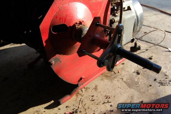 Close-up of a red metal component with a threaded shaft extending from it