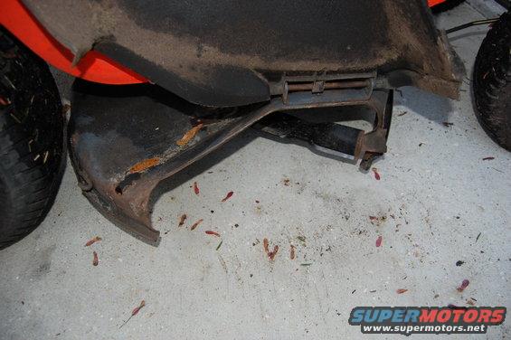 Orange and black vehicle part with rust and a tire on a concrete floor