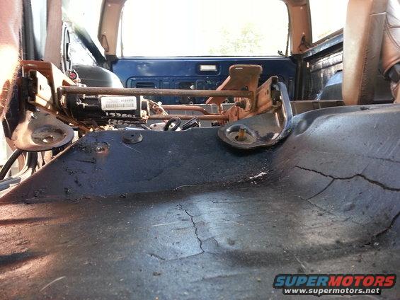 Interior view of vehicle floor with seat mounting hardware visible