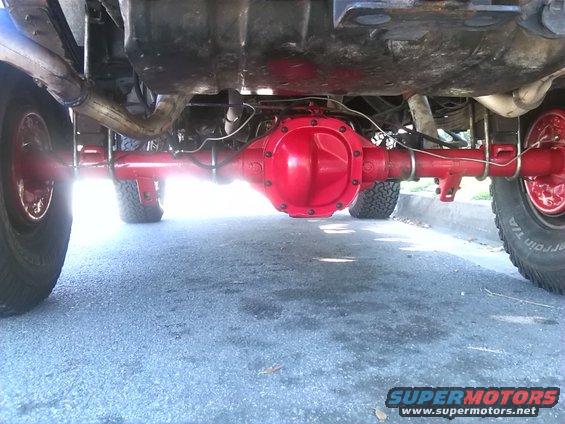 Underside of a vehicle showing a bright red rear differential and suspension components