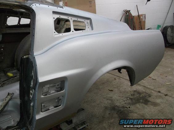 Silver car body panel, rear quarter panel and door frame visible, undergoing restoration