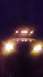 1995 Ford Bronco - A truck is shown at night with its bright headlights and multiple roof lights illuminated.