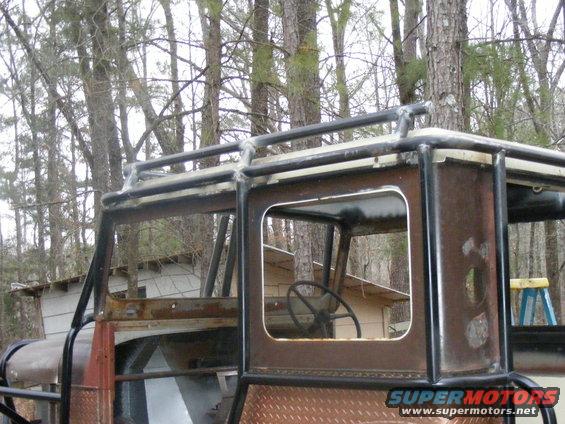 Custom off-road vehicle with roll cage and roof rack, viewed from the side