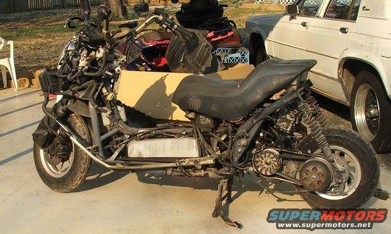 Disassembled scooter with exposed engine and frame, parked outdoors
