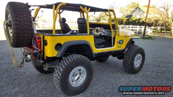 Yellow 1985 Jeep CJ7 with spare tire mounted on the back, roll cage, and aftermarket wheels