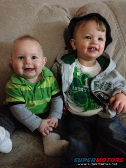 Two smiling children, one in a green striped shirt, the other in a grey hoodie