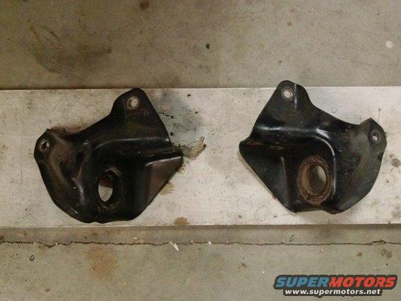 Two black metal brackets on a wooden surface. Text reads SUPERMOTORS