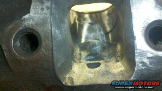 Close-up of an engine cylinder head port with threaded bolt holes visible