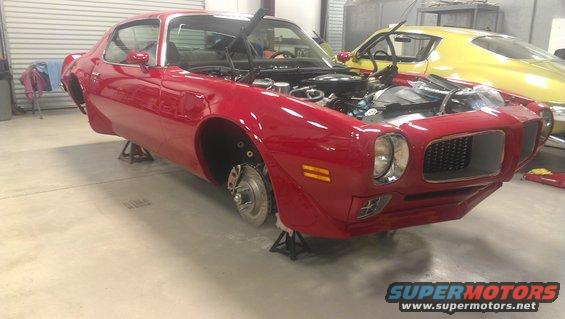 Red 1970 Pontiac Firebird on jack stands with hood open, yellow car behind it