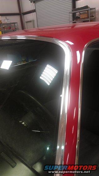 Close-up of red car's roofline and chrome trim around the windshield
