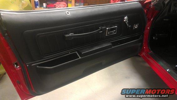 Red car interior with black door panel, chrome handle, and storage compartments