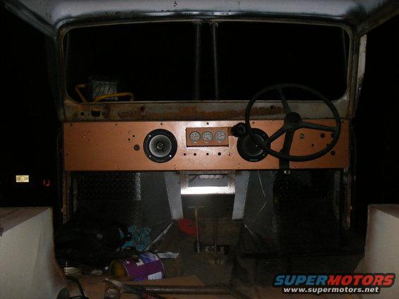 Interior view of a vehicle dashboard with a wooden panel, speakers, and gauges. Steering wheel is visible