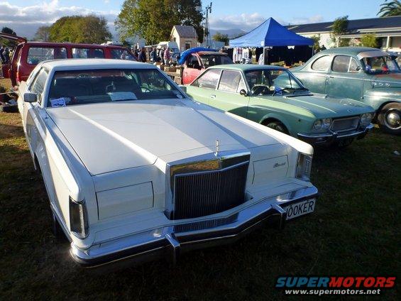 White Lincoln Continental with a prominent chrome grille and rectangular headlights, parked on grass