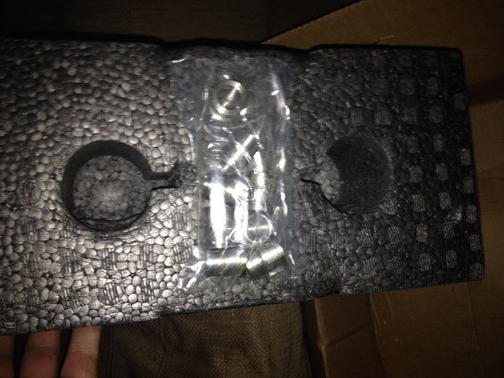 Black foam packaging with a clear plastic bag of metal hardware inside