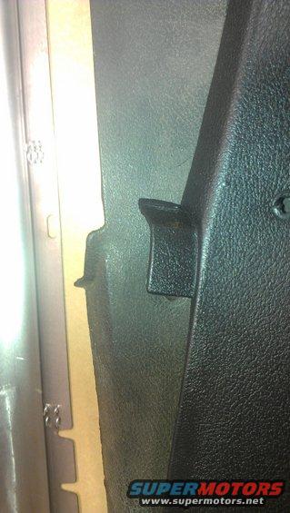 Black textured plastic interior trim panel with a metal bracket visible on the left