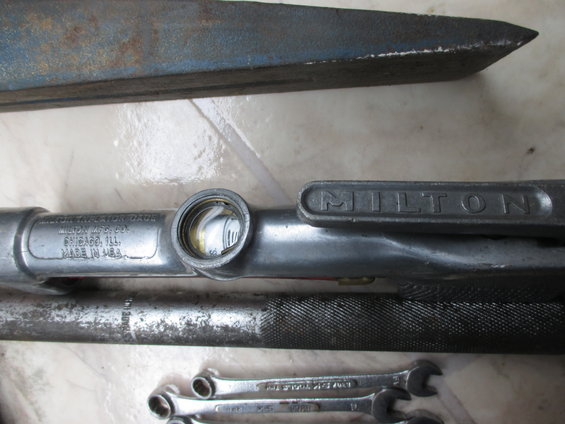 metal tool parts, including a Milton gauge and wrenches